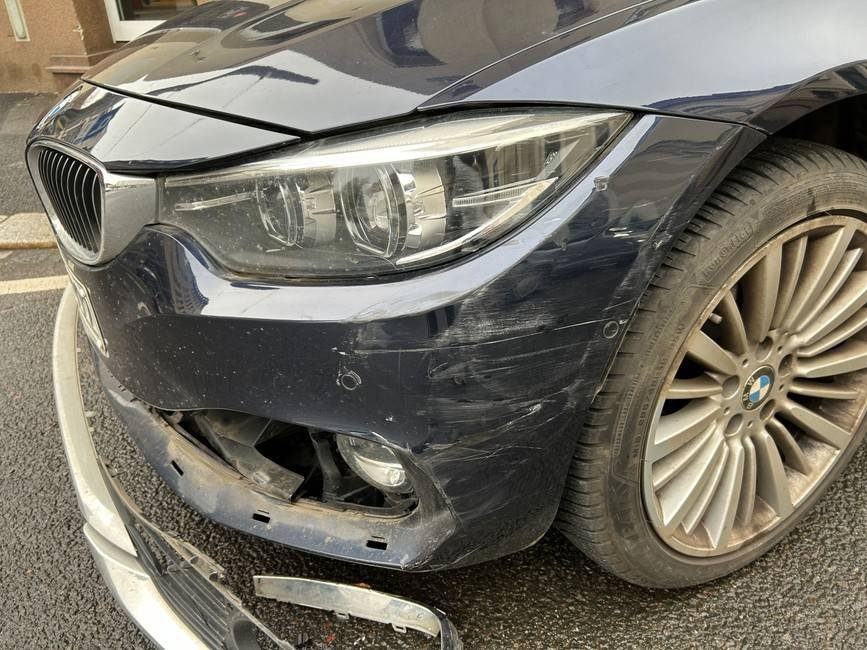 Realer Frontschaden an einem BMW nach unverschuldetem Unfall: Stoßfänger und Kotflügel beschädigt, Lichtbild aus dem Gutachten